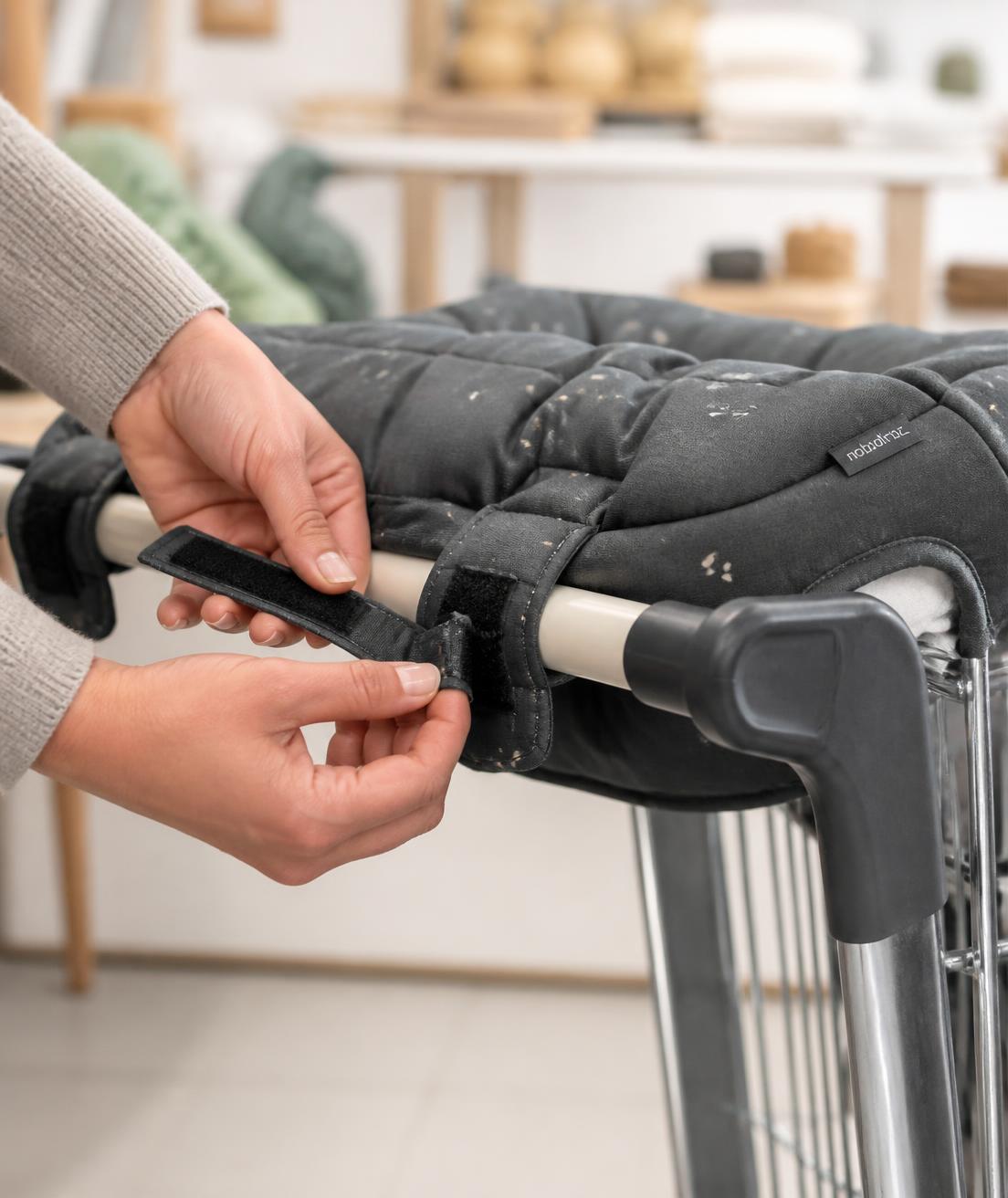 Hands fastening the QuietCart attachment onto a shopping cart handlebar